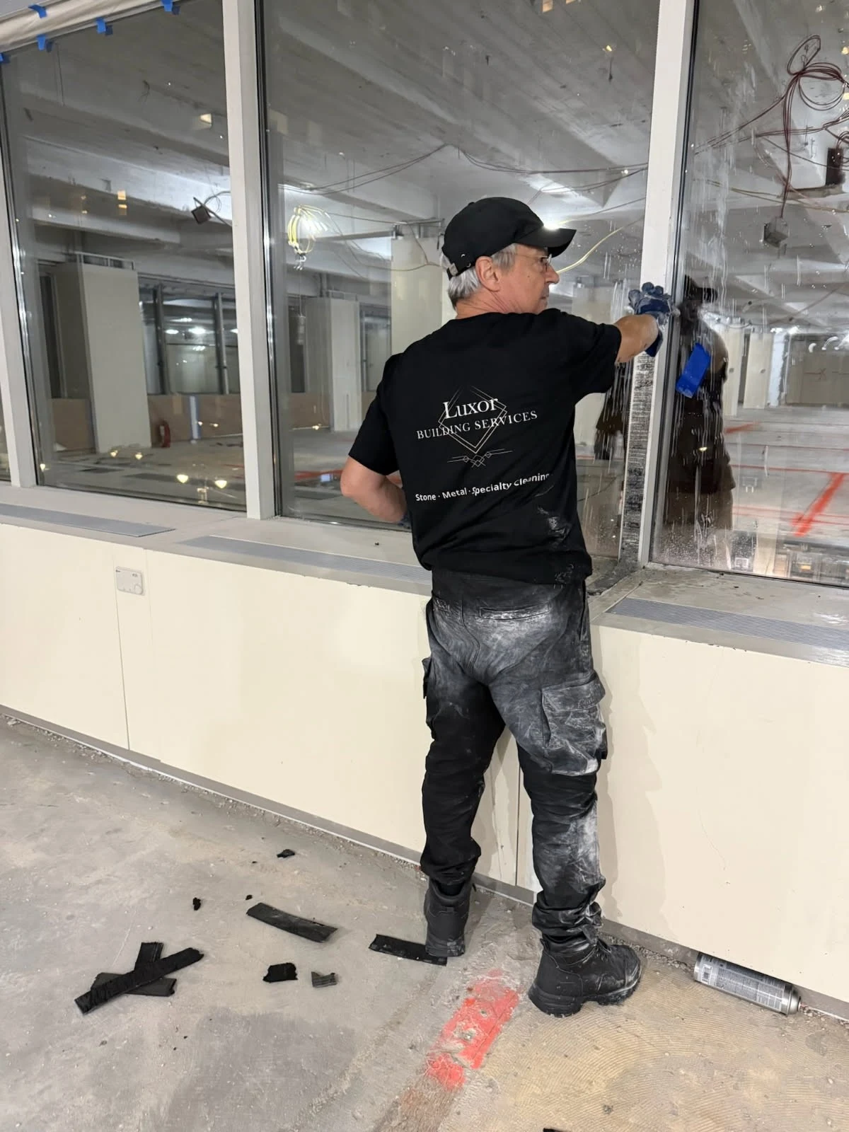 Detail of a Luxor team member cleaning interior glass, with the Luxor uniform visible